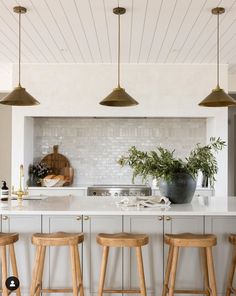 three wooden stools sit in front of an island