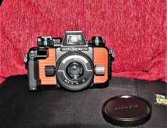 an old fashioned camera sitting on top of a red chair next to a lens cap