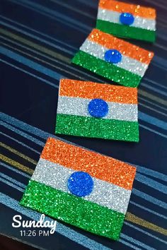 three pieces of paper with the flag of india painted on them, sitting on top of a table