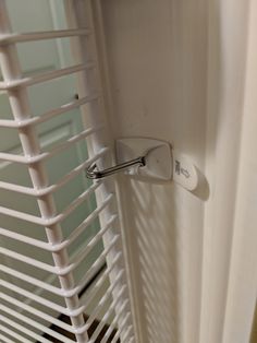 a close up of a door handle on a white curtain with blinds in the background