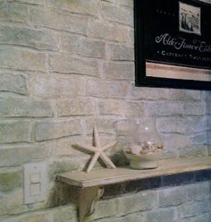 a white brick wall with two starfishs on it and a wine glass sitting on the shelf