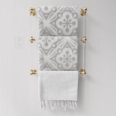 two white towels hanging on the wall with gold hardware and tassels in front of them