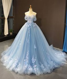 a light blue wedding dress with flowers on the skirt and off the shoulder, is displayed in front of a mannequin