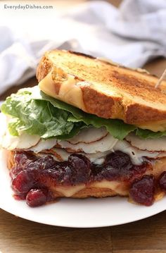 a sandwich with lettuce, cheese and cranberry sauce on a plate