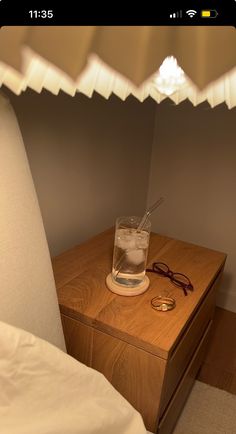 a night stand with glasses on it and a lamp in the corner next to it