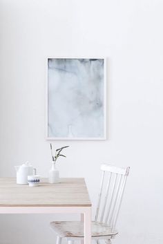 an image of a table with two chairs and a painting on the wall above it