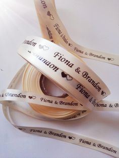 two rolls of personalized ribbon on top of each other with hearts and names printed on them