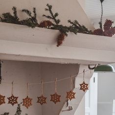 christmas decorations are hanging on the mantle in this room with pine cones and evergreen branches