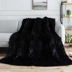 a living room with a couch, chair and black fur rug on the floor in front of a white wall