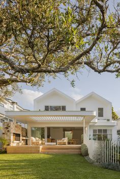 a large white house sitting on top of a lush green field next to a tree