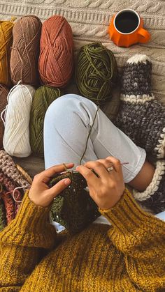 a woman laying on the ground with her hands in her pockets and crocheted balls of yarn behind her