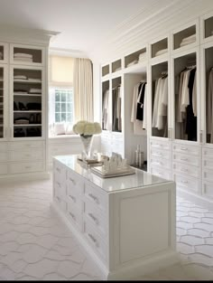 a walk in closet filled with lots of white cabinets and drawers next to a window