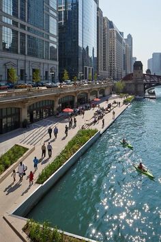 people are walking along the riverbank in chicago, illinois as kayakers paddle down it