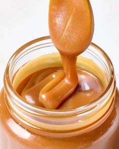 a jar filled with caramel sauce and a wooden spoon sticking out of the top