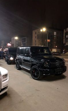 several vehicles are parked on the street at night