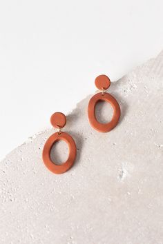 an orange pair of earrings sitting on top of a white surface