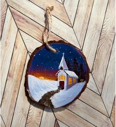 a wooden ornament with a painting of a church in the snow on it