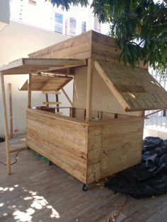 a small wooden structure sitting on top of a hard wood floor next to a tree