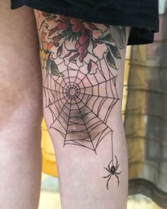 a spider and web tattoo on the leg