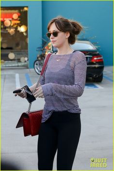 a woman in black and white striped shirt carrying a red purse