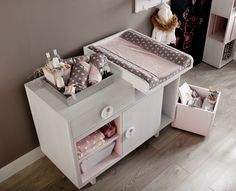 a baby's changing table in the corner of a room next to a teddy bear