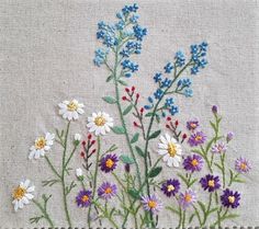 a bunch of flowers that are sitting on a piece of cloth with stitching in it