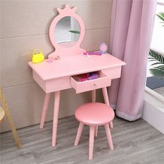 a pink vanity table with stool and mirror