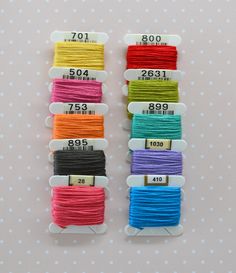 six spools of thread in different colors on a white background with polka dots