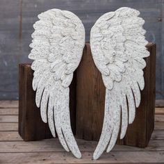 two white angel wings sitting on top of a wooden block