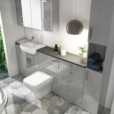 a white toilet sitting next to a bathroom sink under a light hanging from a ceiling fixture