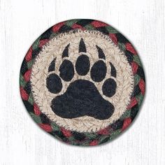 a black and white dog paw on a round rug with red, green and beige braiding