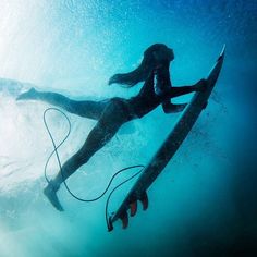 a woman is swimming in the ocean with her surfboard and holding on to it