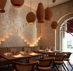 an empty restaurant with several tables and chairs, hanging lights above the dining room table