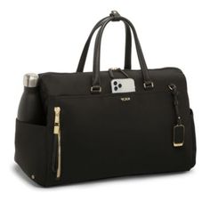 a black handbag with gold zippers on the front and side pockets, it has a cell phone in the pocket