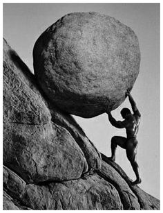 a black and white photo of a man pushing a rock on top of a mountain