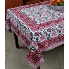 a bowl of fruit sitting on top of a table covered in a red and green cloth