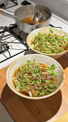 two bowls filled with food sitting on top of a wooden counter next to a stove