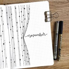 an open notebook with the word november written in cursive writing on it next to two markers