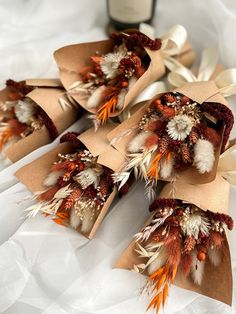 four brown paper bags with dried flowers on them and a bottle of wine in the background