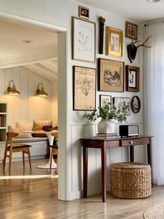 a living room filled with furniture and framed pictures on the wall above a wooden table