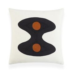 a black and orange pillow with two circles on the front, sitting on a white surface