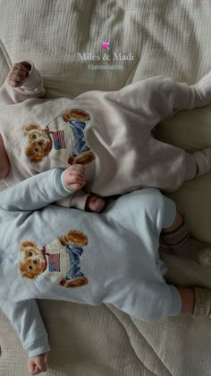 a baby laying on top of a bed next to a teddy bear