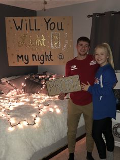 a man and woman standing in front of a bed holding up a sign that says, will you grant me my night?