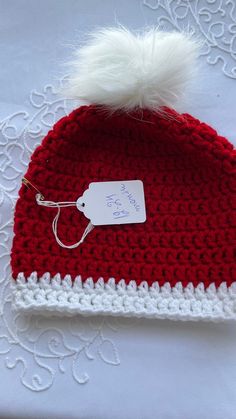 a red and white crocheted hat with a tag on it