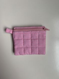 A pink coin purse with a gingham print on the outside and inside with a small pink handle on the outside that can be used for a keychain. it also includes some white bias tape on the inside. This coin purse can fit some cards, cash, or any similar small items. Cute Pink Coin Purse With Card Slots, Pink Rectangular Coin Purse With Card Slots, Pink Coin Purse With Card Slots For Personal Use, Pink Pouch Coin Purse With Zipper, Pink Coin Purse With Card Slots For Daily Use, Cute Pink Coin Purse With Zipper Closure, Pink Pouch Coin Purse With Card Slots, Cute Pink Coin Purse With Zipper, Cute Pink Pouch Coin Purse