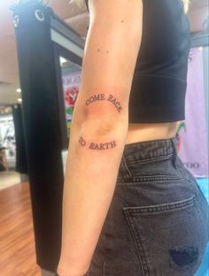 a woman's arm with the words come back to earth tattooed on it