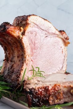 a piece of meat sitting on top of a cutting board next to some green leaves