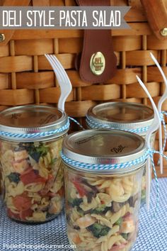 three jars filled with pasta sitting on top of a table next to a wicker basket