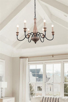 a chandelier hanging from the ceiling in a living room with white walls and windows