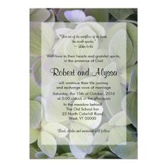 a wedding card with white flowers in the middle and green leaves around it, on top of